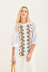 Camisa blanca de voile con rayas finas, corte amplio, cartera con botones y bordado de flores en el frente.