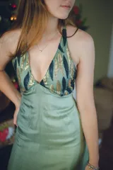 Vestido largo color marrón cobrizo con escote en V, cut outs laterales bajo el busto y breteles finos que se cruzan y atan en la espalda. Presenta un top con estampado abstracto en tonos marrones y dorados.