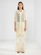 Camisa larga italiana confeccionada en punto abierto de algodón color crudo, con cuello clásico, manga tres cuartos y cierre frontal con botones.