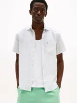 Camisa blanca de lino con estampado de motivos náuticos en azul, de corte regular, manga corta, cuello camisero clásico, cierre con botones y bolsillo en el pecho.