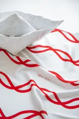 Pañuelo de seda con estampado que evoca ondas del mar, en tonos blanco y marrón.