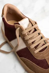 Zapatillas deportivas marrones con detalles en color borgoña y blanco, con cordones y suela de goma.