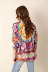 Camisa de mangas largas con cuello clásico y cierre frontal con botones. Estampado multicolor con motivos florales y geométricos.