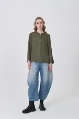 Blusa blanca de poliéster, entallada, con escote en V y botones frontales. Presenta mangas largas con puños anchos.