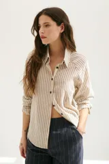 Camisa a rayas verticales color beige y blanco, con cuello clásico, botones marrones y mangas largas.