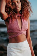 Top dorado de tejido de punto con lurex, corte halter, espalda descubierta y abertura en el pecho.