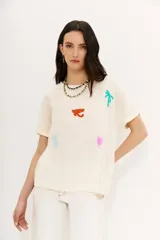 Remera color crudo de corte holgado con mangas cortas rebatidas y bordados de motivos egipcios en hilo de colores.