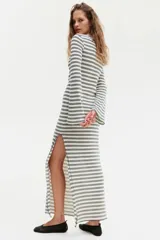 Vestido largo de punto texturizado a rayas horizontales en blanco y negro. Tiene cuello redondo, mangas largas y tajo lateral pronunciado.