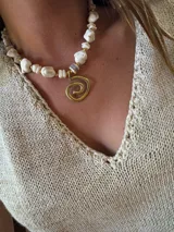 Collar de piedras irregulares color blanco con detalles dorados y dije en espiral dorado.
