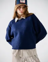 Buzo de tejido melange azul oscuro, con cuello redondo y mangas largas, corte cropped y calce holgado.
