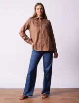 Camisa marrón de lyocell, marca Dash. Cuello con solapa y abertura central con botones. Largo de manga regulable con presilla y botón. Delantera con bolsillos aplicados.