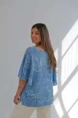 Blusa celeste con estampado de flores blancas y azules, de corte amplio y mangas cortas.