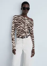 Camiseta de manga larga con estampado animal print de cebra en tonos marrones y beige. Tiene cuello asimétrico y corte ajustado.