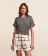 Conjunto de pijama corto compuesto por una remera gris de manga corta con bolsillo en el pecho y un short con estampado de cuadros blancos y grises.