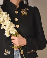 Chaqueta negra de lana y cashmere, con cuello mao, botones metálicos dorados y detalles bordados en puños y ruedo.
