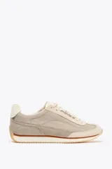 Zapatillas deportivas tipo running color beige y gris claro, con detalles en cuero y gamuza. Cierre con cordones.