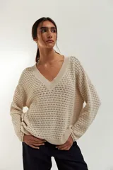 Sweater de punto calado color crudo, con escote en V y mangas largas.