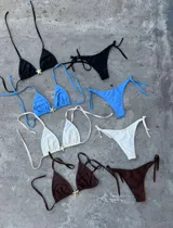 Conjunto de bikini color crema con corpiño triangular con detalle de estrella dorada y bombacha con tiras laterales.