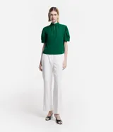 Blusa verde esmeralda de crepé con cuello alto, botones dobles y pequeña abertura en el cuello. Tiene mangas cortas abullonadas con botones.