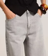 Bermuda femenina confeccionada en jeans color gris oscuro, modelo jorts, con trabillas en la cintura y bolsillos.