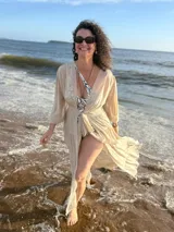 Túnica larga de gasa color beige claro, con mangas largas y cuello en V, con detalle de amarre frontal.