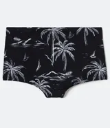 Sunga de poliéster con cintura elástica y cordón interno para ajuste. Presenta un estampado tropical con palmeras, montañas y veleros en blanco sobre fondo negro.