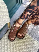 Sandalias de cuero vacuno color marrón, con pulsera superior desmontable y hebillas laterales para ajuste.