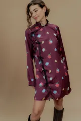 Vestido corto color borgoña con estampado de rosas y limones, mangas largas, cuello mao y cierre lateral con lazos negros.