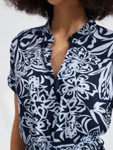 Vestido corto con estampado floral en tonos azul y blanco, con cuello en V, mangas cortas y lazo en la cintura.