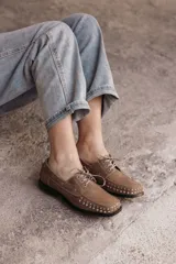 Mocasín de cuero negro con cordones y tachas metálicas en la puntera.