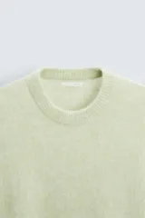 Sweater verde claro tejido con lana y alpaca, de corte regular, cuello redondo y manga larga con terminaciones en rib.