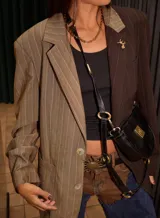 Blazer oversize con diseño asimétrico, mitad en tela a cuadros gris y blanco, mitad en tela lisa gris. Tiene solapas, cierre con botones y pin de salchicha decorativo.