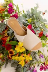 Sandalia plana color beige con tiras anchas cruzadas en el empeine y tira elástica en el talón.