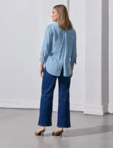 Camisa celeste de tencel con cuello con solapa, escote en V, abertura central con botones y mangas 3/4 regulables con presilla y botón.