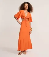Vestido largo color naranja vibrante, con escote en V profundo que se anuda al frente, mangas amplias tipo mariposa y recortes laterales en la cintura.