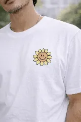 Remera blanca de manga corta con cuello redondo y un parche bordado de una flor sonriente en el pecho izquierdo.