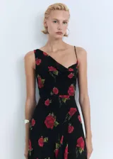 Vestido largo negro con estampado de rosas rojas, escote asimétrico con drapeado y bretel fino en un hombro.