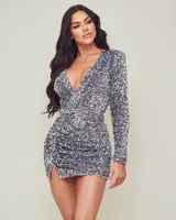 Vestido corto de fiesta plateado con lentejuelas, escote en V pronunciado y mangas largas.