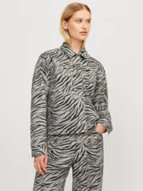 Chaqueta tipo camisa de manga larga con cuello clásico y bolsillos en el pecho. Estampado de cebra en tonos grises y negros.