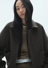 Chaqueta marrón con forro interior, cierre delantero con cremallera, dos bolsillos laterales, cuello camisero, diseño oversize y manga larga abotonada.