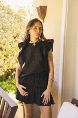 Minifalda negra de lino con detalle fruncido en todo el cuerpo y ruedo con volado amplio. Tiene cintura elástica.