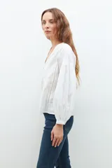 Blusa lila con bordados, de mangas largas abullonadas y cuello en V.