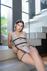 Conjunto de lencería de encaje bitono blanco y negro, compuesto por un corpiño tipo bralette con breteles finos y tanga de tira doble regulable a la cintura. Incluye portaligas desmontable y ligas regulables.