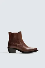 Bota de cuero color marrón, estilo cowboy, con caña corta, puntera en punta y tacón cubano.