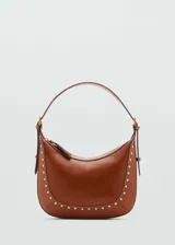 Bolso marrón de cuero con forma de media luna, asa corta y tachas doradas.