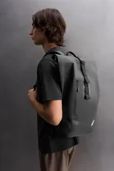 Mochila negra de tejido técnico con compartimento principal con cierre de hebilla de liberación rápida, bolsillo termosellado frontal con cremallera, asa de mano y dos asas de hombro ajustables.
