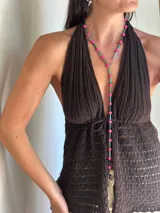 Collar largo de diseño versátil con bastones de vidrio facetados y cuentas de piedra en color fucsia. Incluye herrajes de acero quirúrgico que permiten ajustar su forma, pudiendo utilizarse como corbatín.