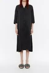 Vestido camisero midi negro de corte holgado, con cuello camisero, mangas 3/4 y cierre frontal con botones.