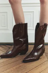 Bota de cuero color bordó, estilo cowboy, con puntera marcada y tiradores laterales.