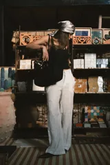 Pantalón de vestir negro de tiro alto, corte recto y pierna ancha. Presenta pliegues frontales y bolsillos laterales.